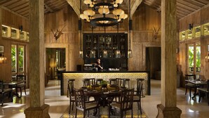 A spacious bar area with a central bar counter, surrounded by multiple seating options including a round table with chairs and additional bar stools.