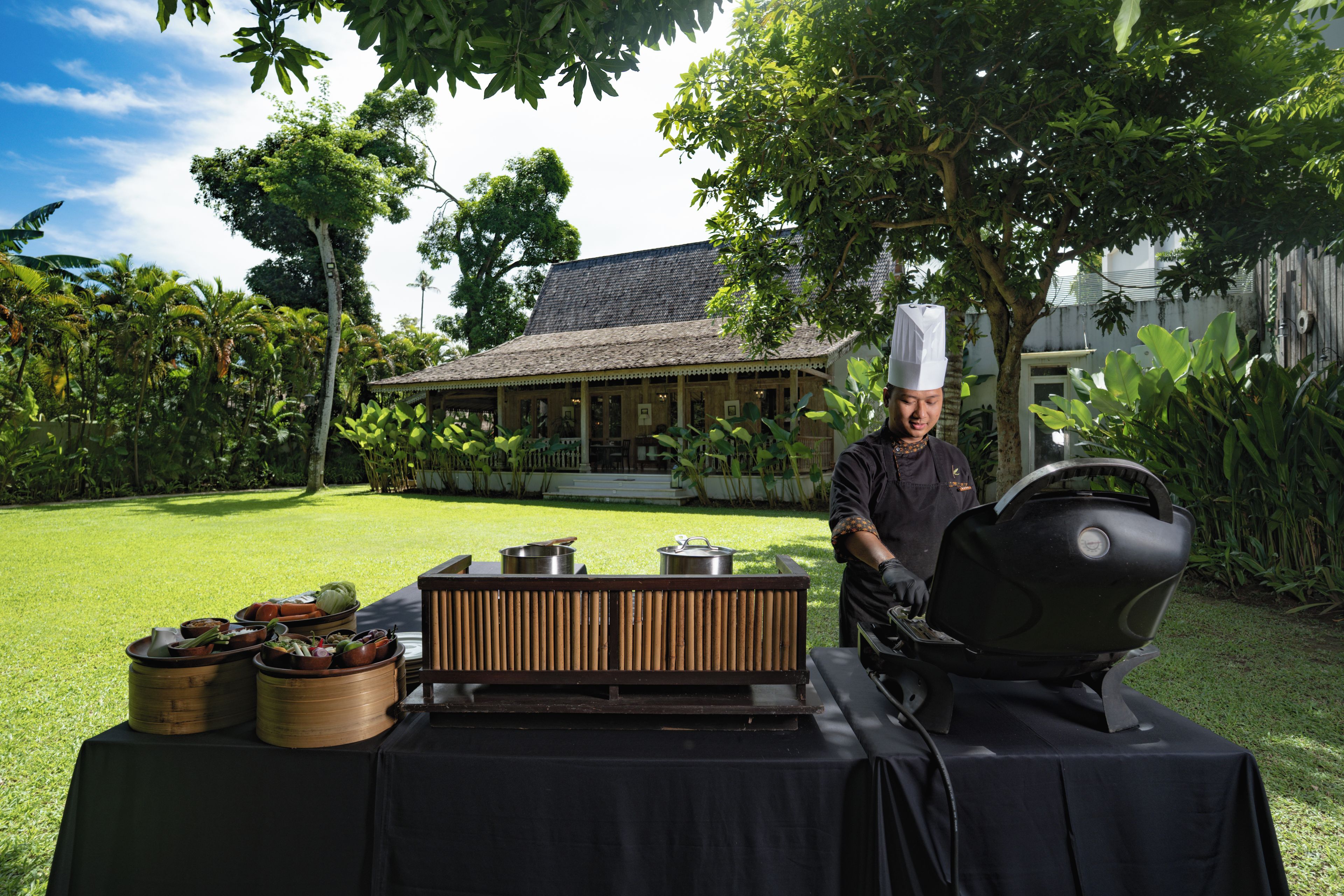 Un espace de cuisson extérieur équipé d’un barbecue, de casseroles et d’une table sur laquelle sont disposés des aliments.
