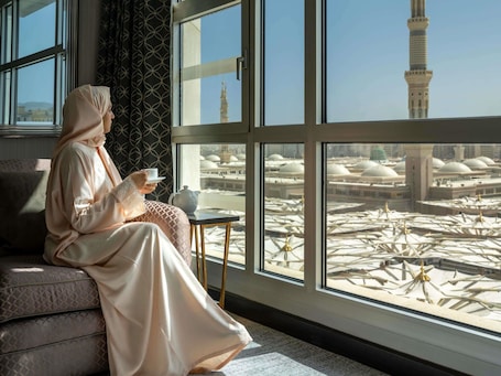 A room with large windows overlooking a mosque with multiple domes and a minaret.