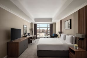 Una habitación de hotel con una cama grande, un escritorio, una televisión y vistas a la ciudad.