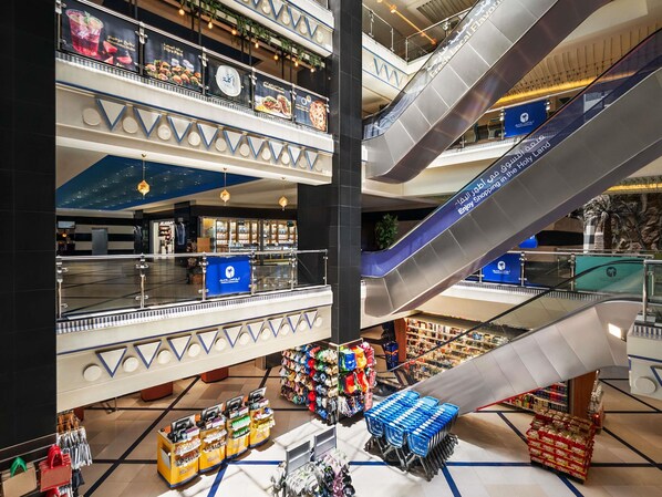 Un centro comercial de varios niveles con escaleras mecánicas, un atrio central y diversas tiendas.