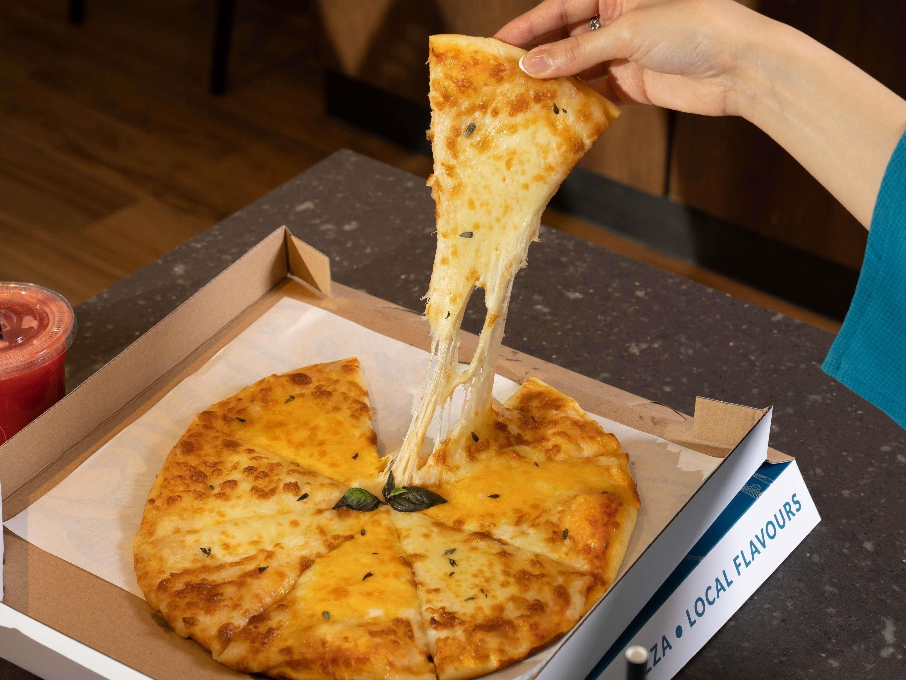 A pizza box with a slice being lifted, revealing melted cheese.