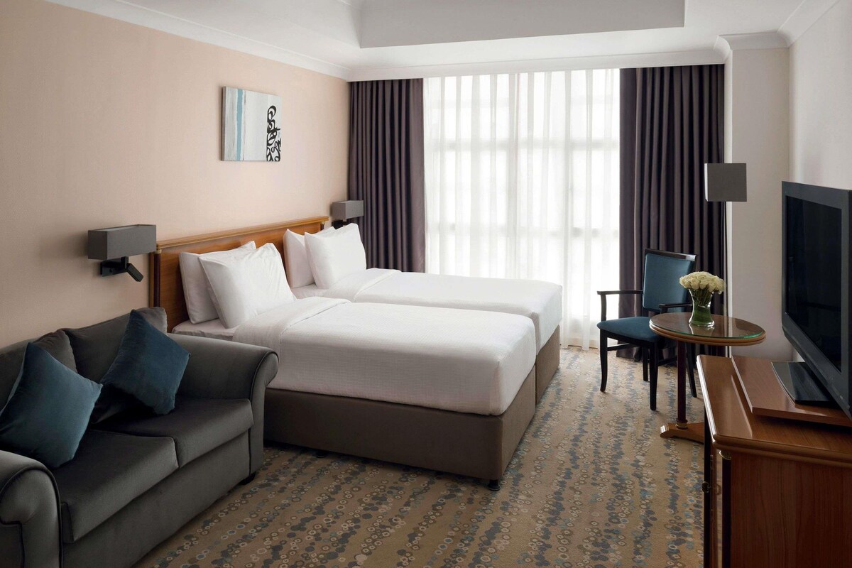Una habitación de hotel con cama, sofá, televisión y escritorio.
