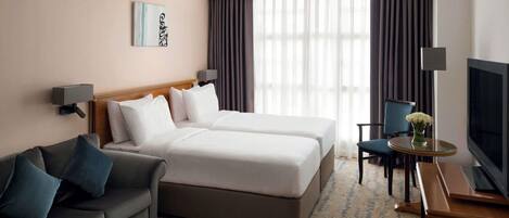 A hotel room with a bed, a sofa, a TV, and a desk.