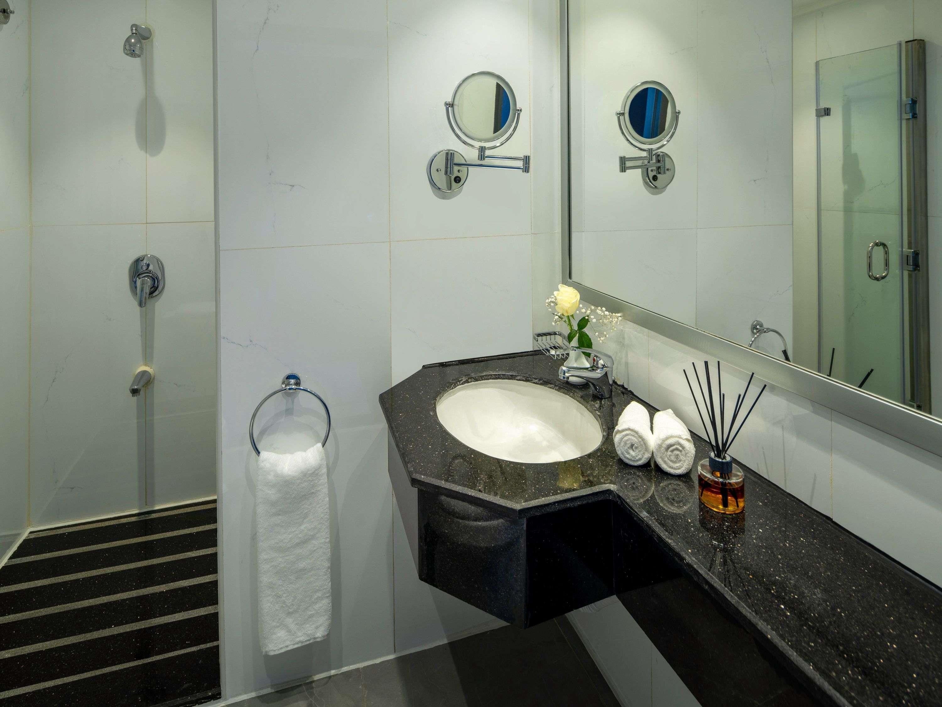 A modern bathroom with a shower, a sink with a mirror, and a towel rack.