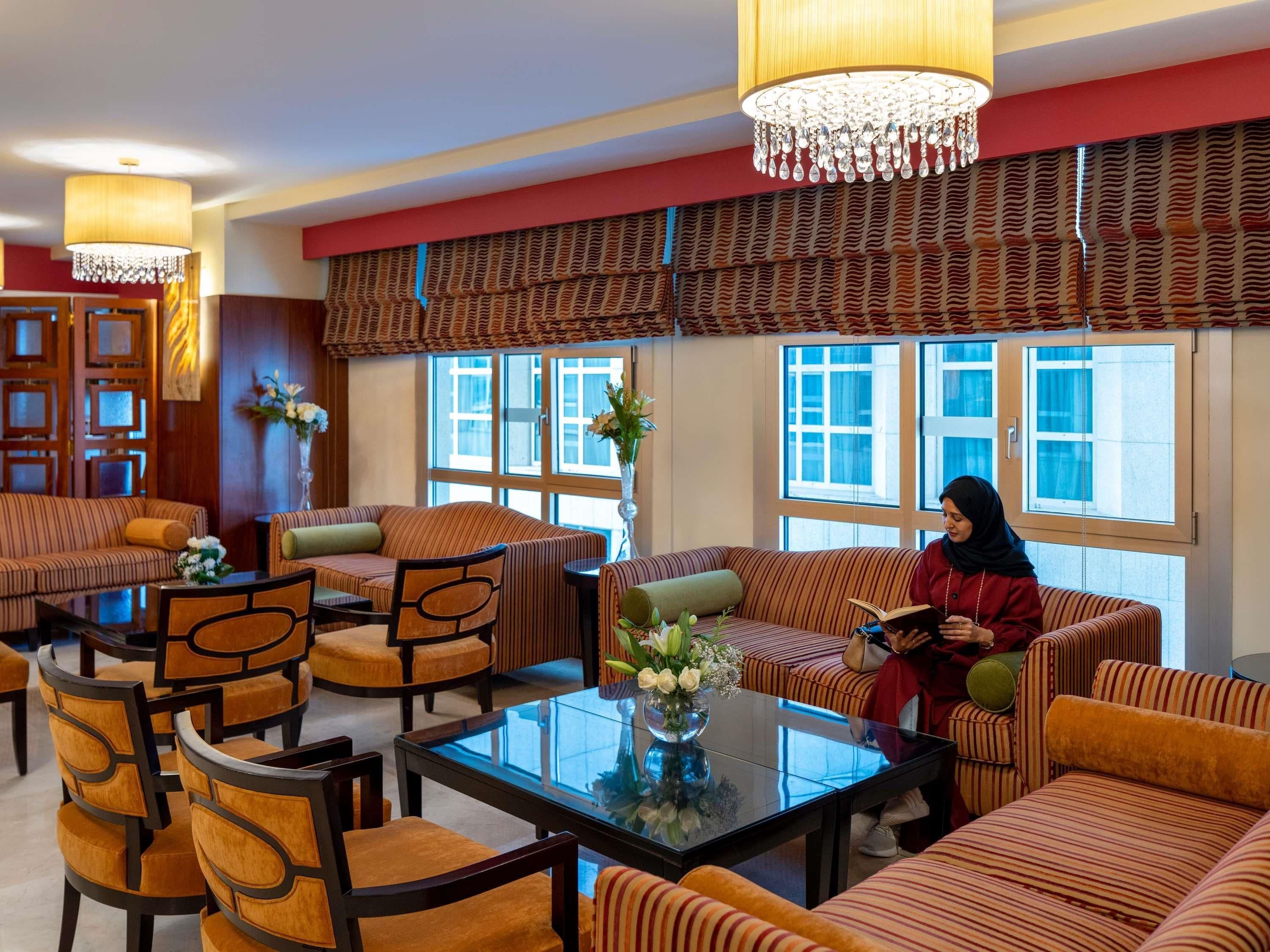 A hotel lobby with striped sofas, a glass coffee table, and a chandelier.