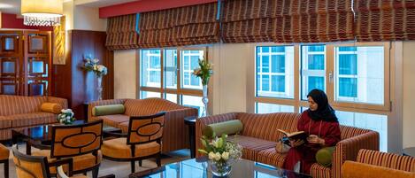 A hotel lobby with striped sofas, a glass coffee table, and a chandelier.