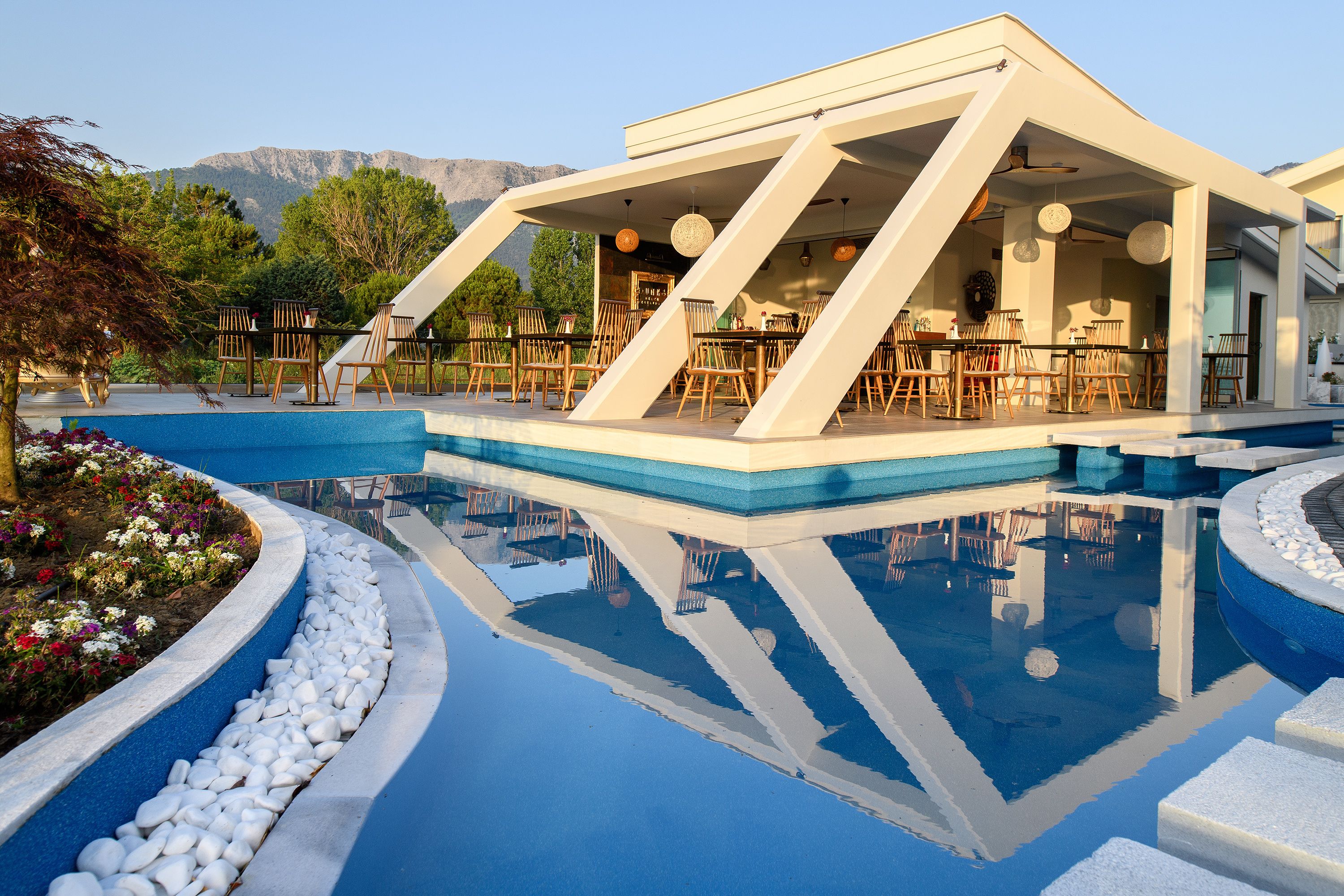 A modern outdoor pool area with a dining setup and mountain views.
