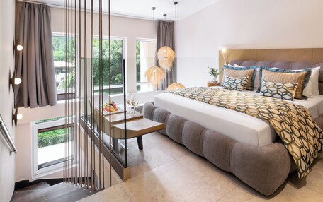 A modern bedroom with a large bed, a small table with a glass top, and a hanging light fixture.