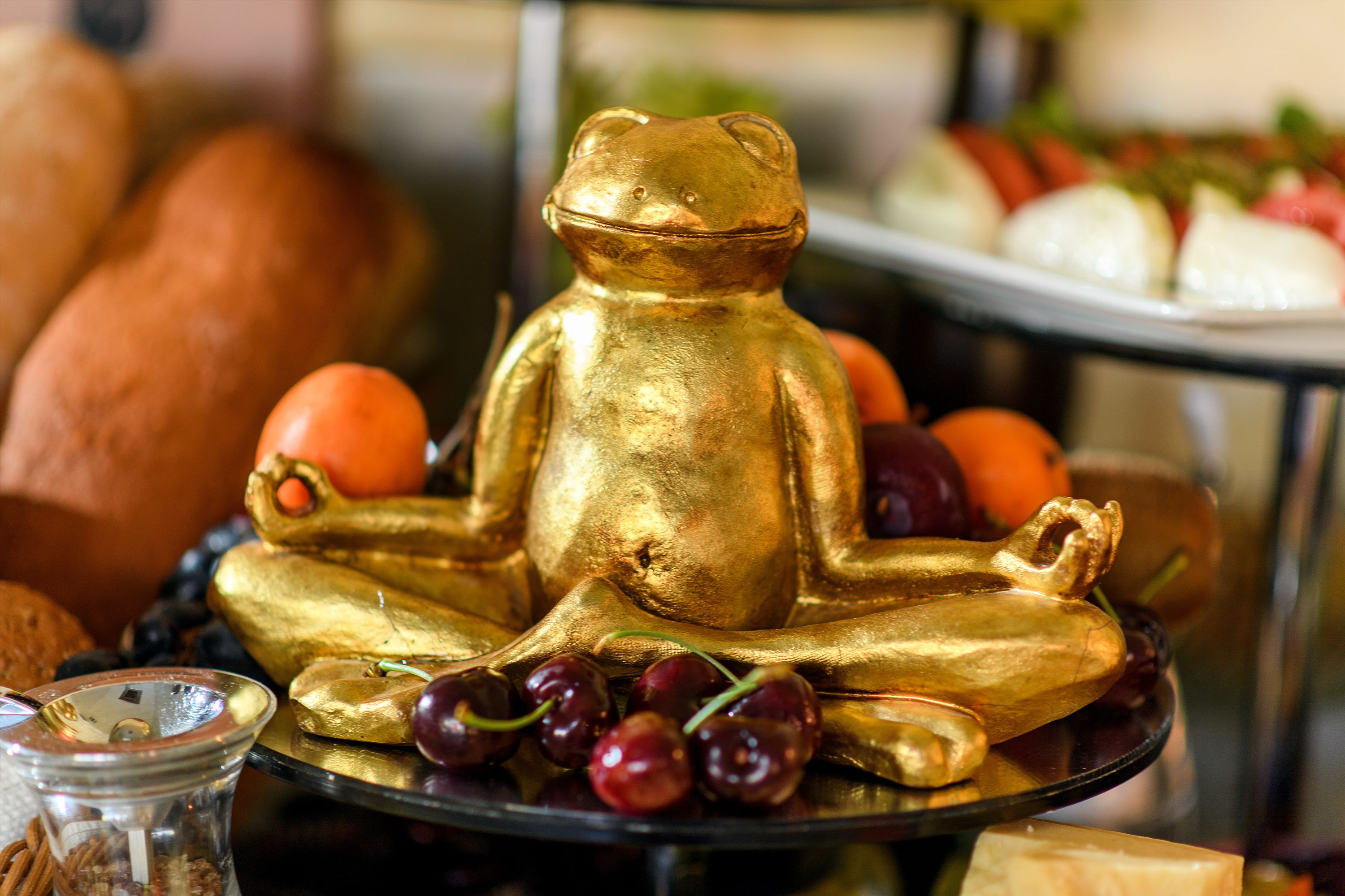 A gold bear figurine on a tray with grapes and oranges.