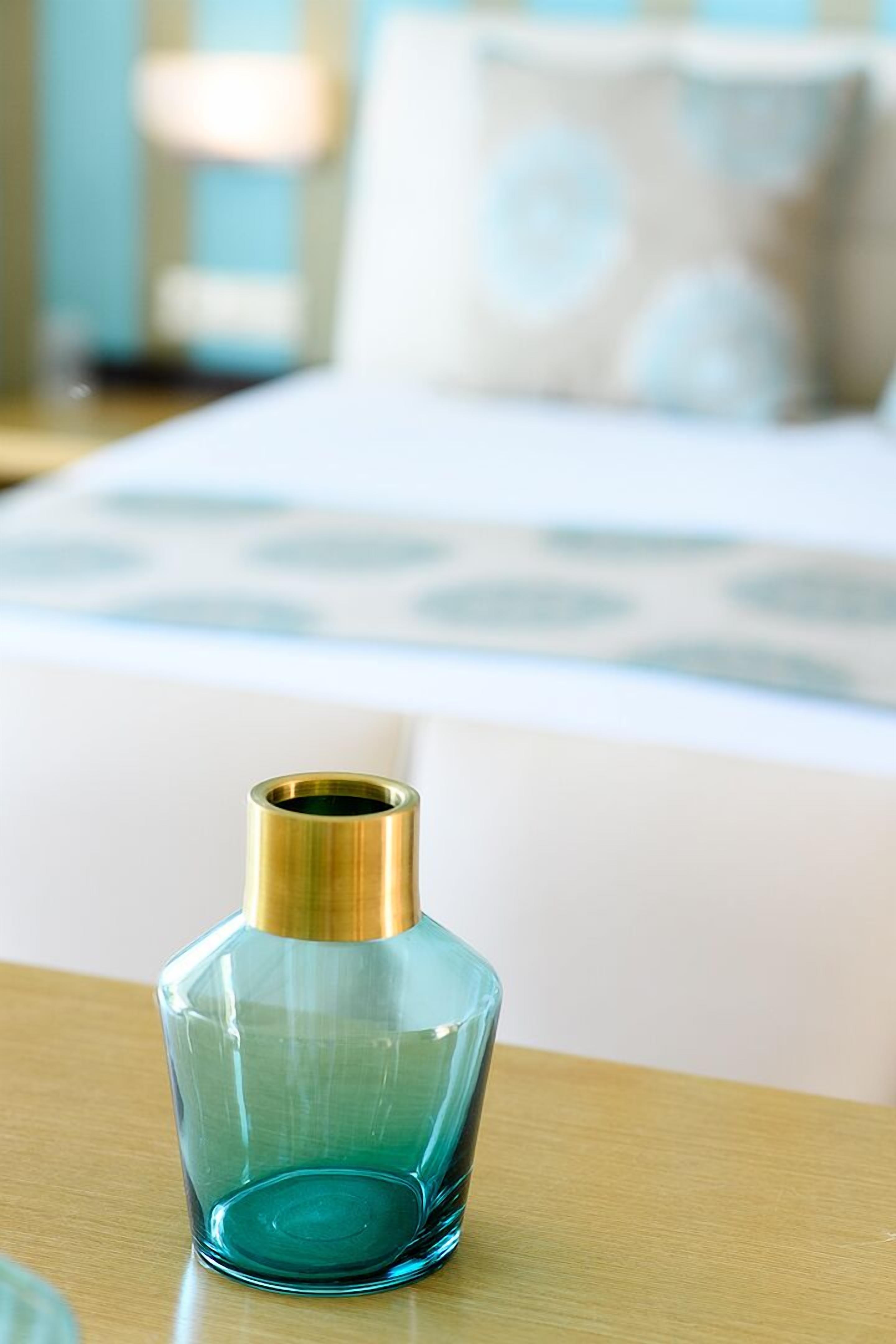 Una botella de vidrio transparente con tapón dorado sobre una superficie de madera.
