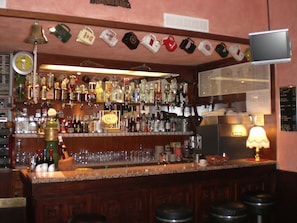 A bar area with a variety of liquor bottles, glasses, and a bell. - Hotel Nettuno (Diano Marina)