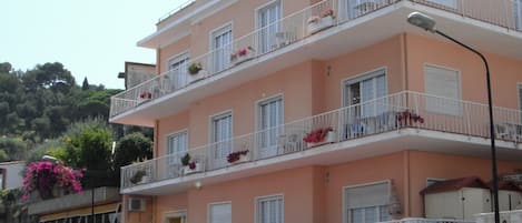 A multi-story hotel with balconies, a restaurant, and a car parked in front.