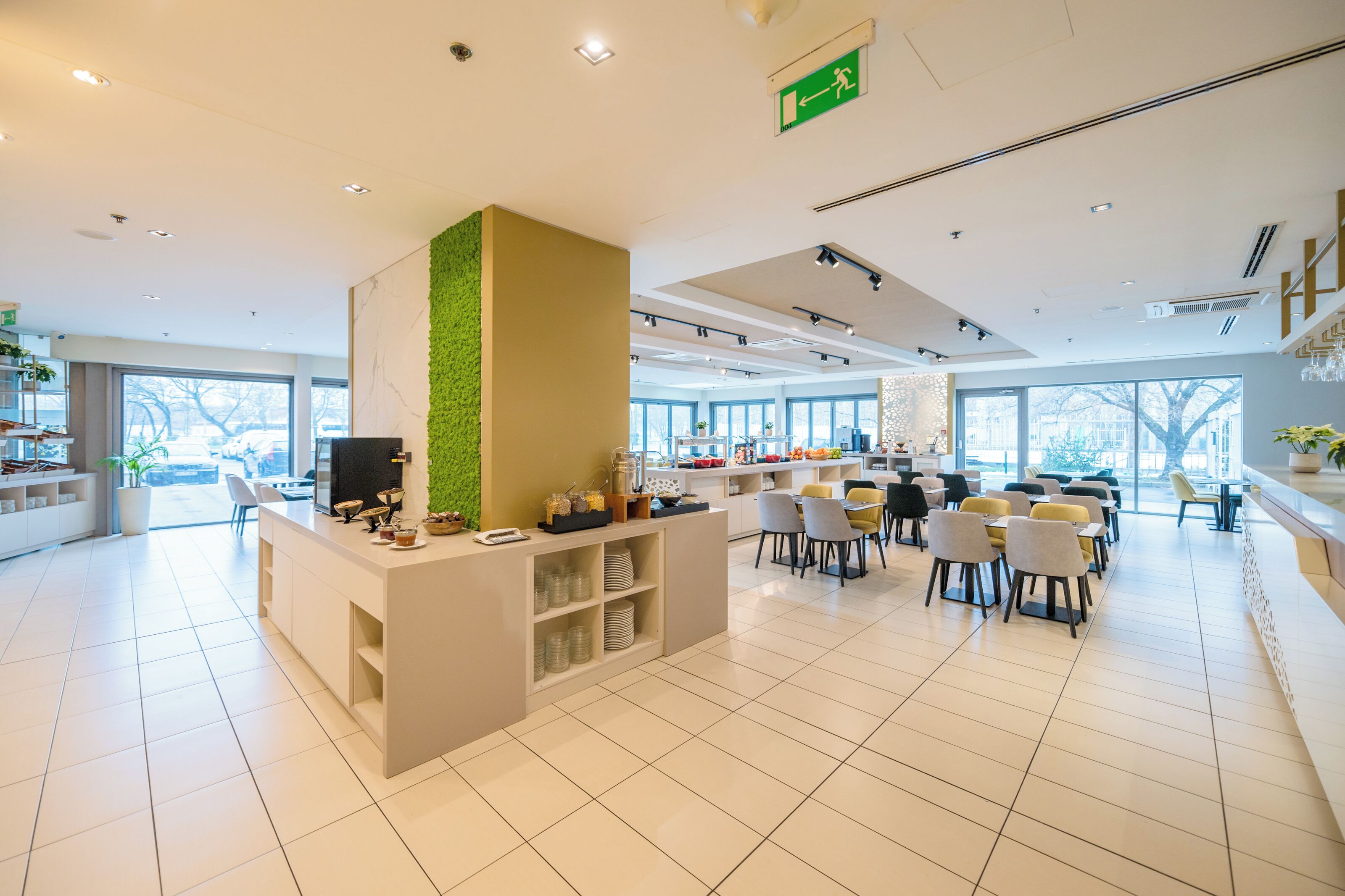 Un hall d’hôtel moderne avec un comptoir d’accueil, un espace salon et de grandes fenêtres.