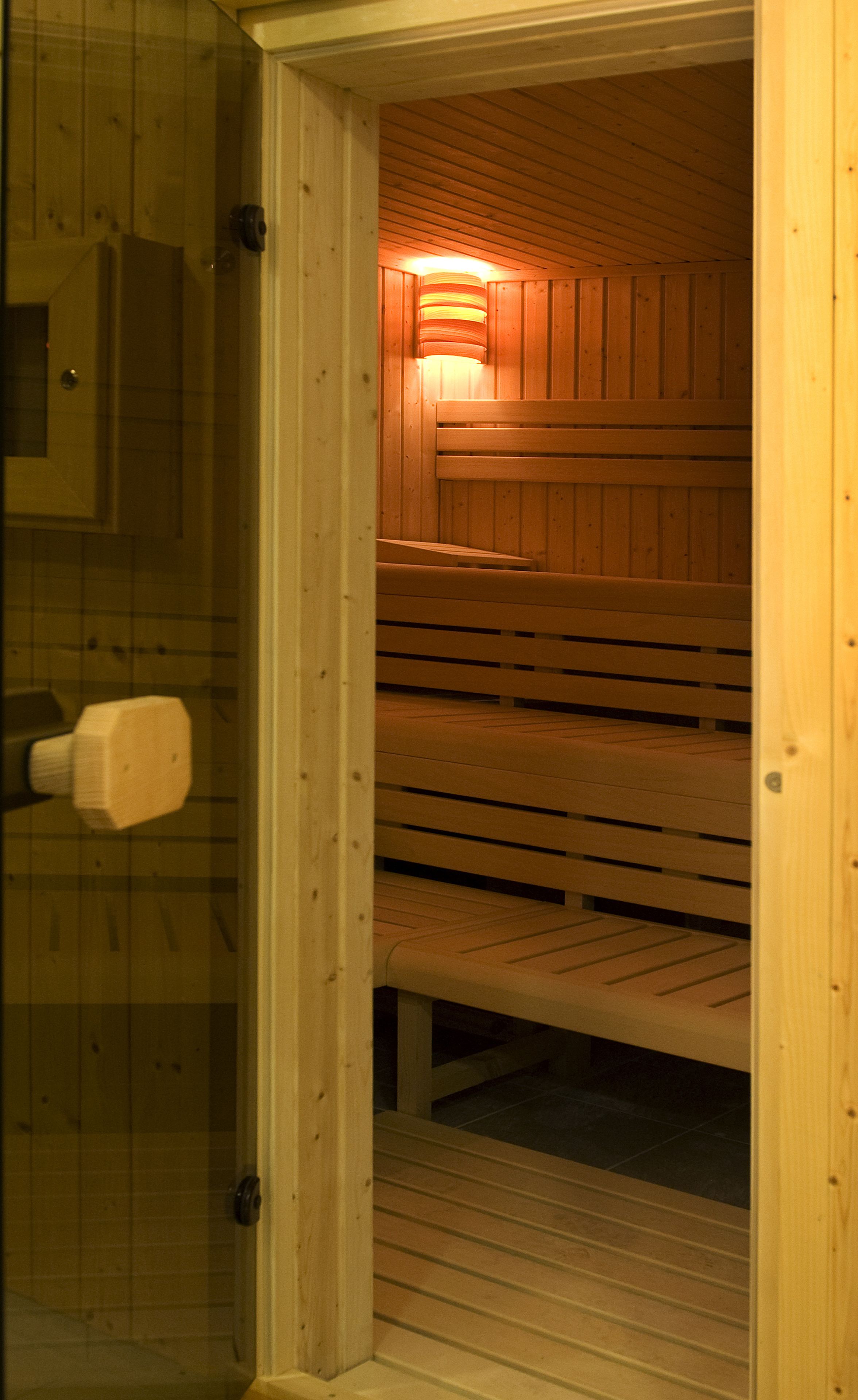 A sauna with wooden benches and a glass door.