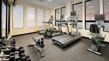Un gimnasio con cintas de correr, elípticas y mancuernas.