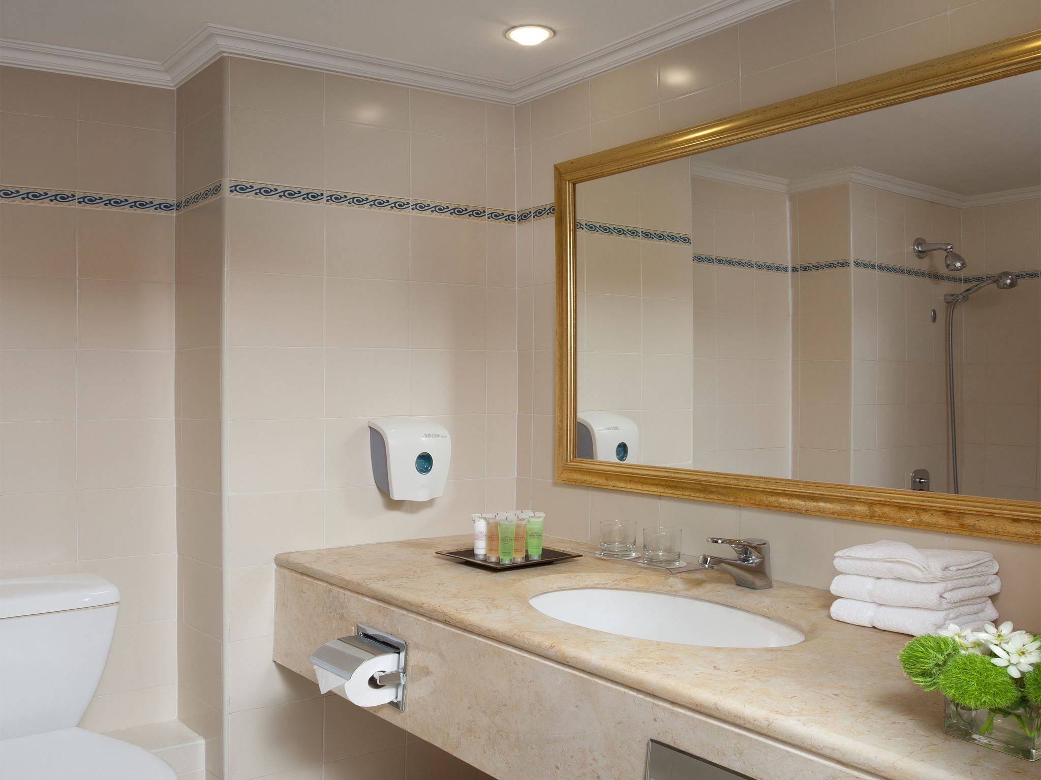 A bathroom with a sink, mirror, toilet, and hand dryer.