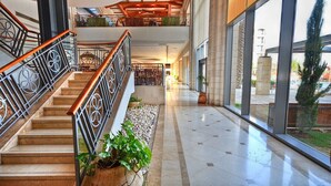 A spacious indoor area with a central staircase, large windows, and a view of the outside. - Golden Crown Hotel (Nazareth)