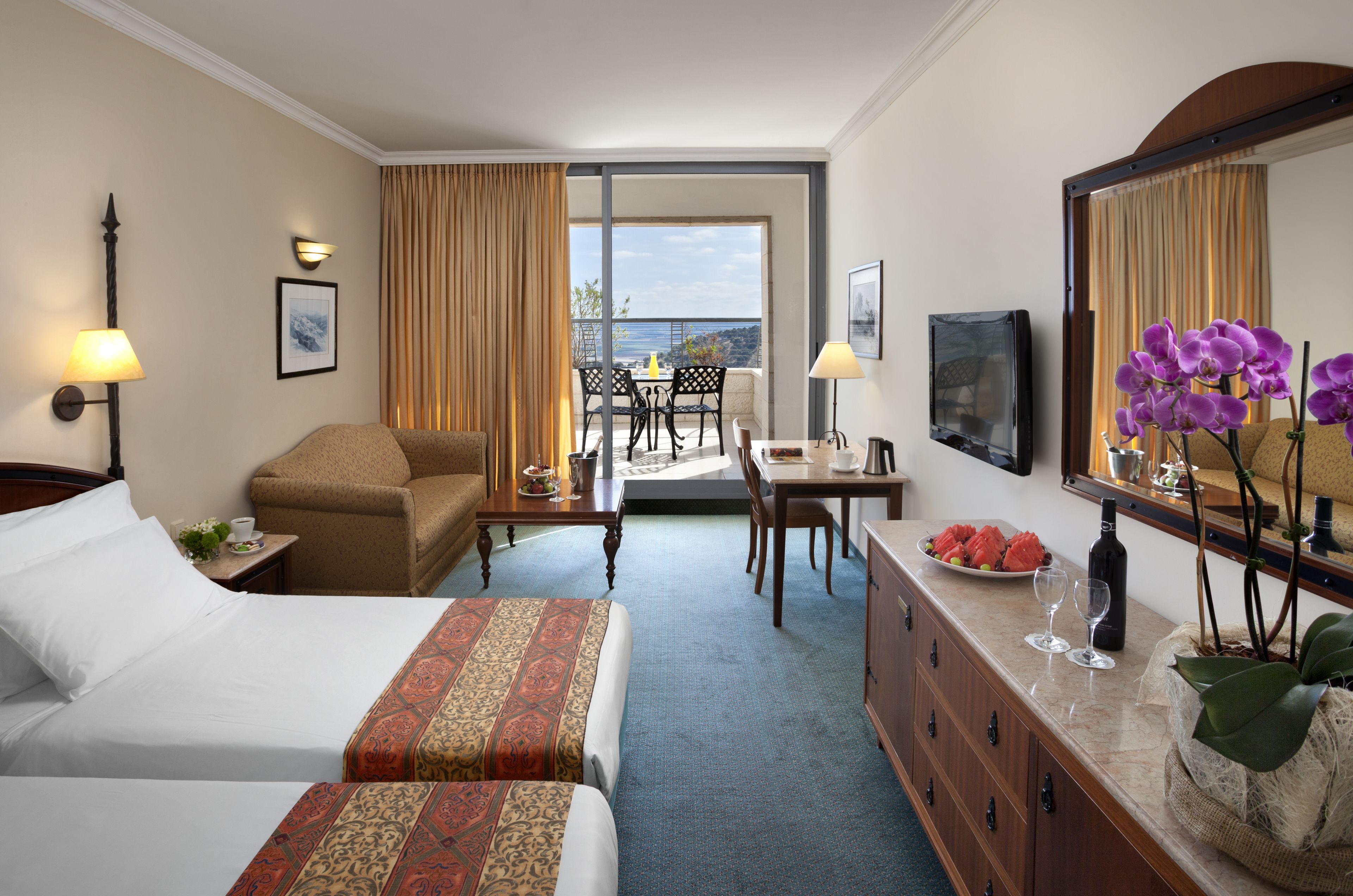 Quarto de hotel com duas camas, uma escrivaninha, uma cadeira, uma mesa de jantar e uma varanda com vista.