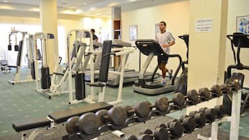 Un gimnasio con cintas de correr, máquinas de pesas y un banco.