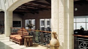 A spacious interior with a high ceiling, a seating area with wooden furniture, and a large window providing natural light. - Golden Crown Hotel (Nazareth)