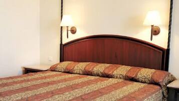A hotel room with a wooden bed, two bedside lamps, and a patterned bedspread.