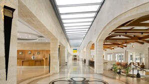 A spacious lobby with a high ceiling, a reception desk, and a central decorative floor pattern. - Golden Crown Hotel (Nazareth)