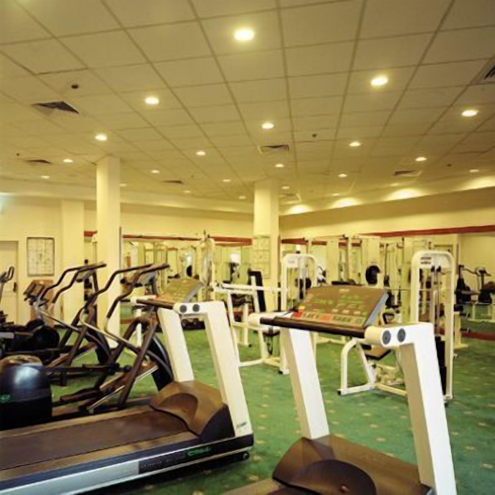 Un gimnasio con cintas de correr, elípticas y máquinas de pesas.