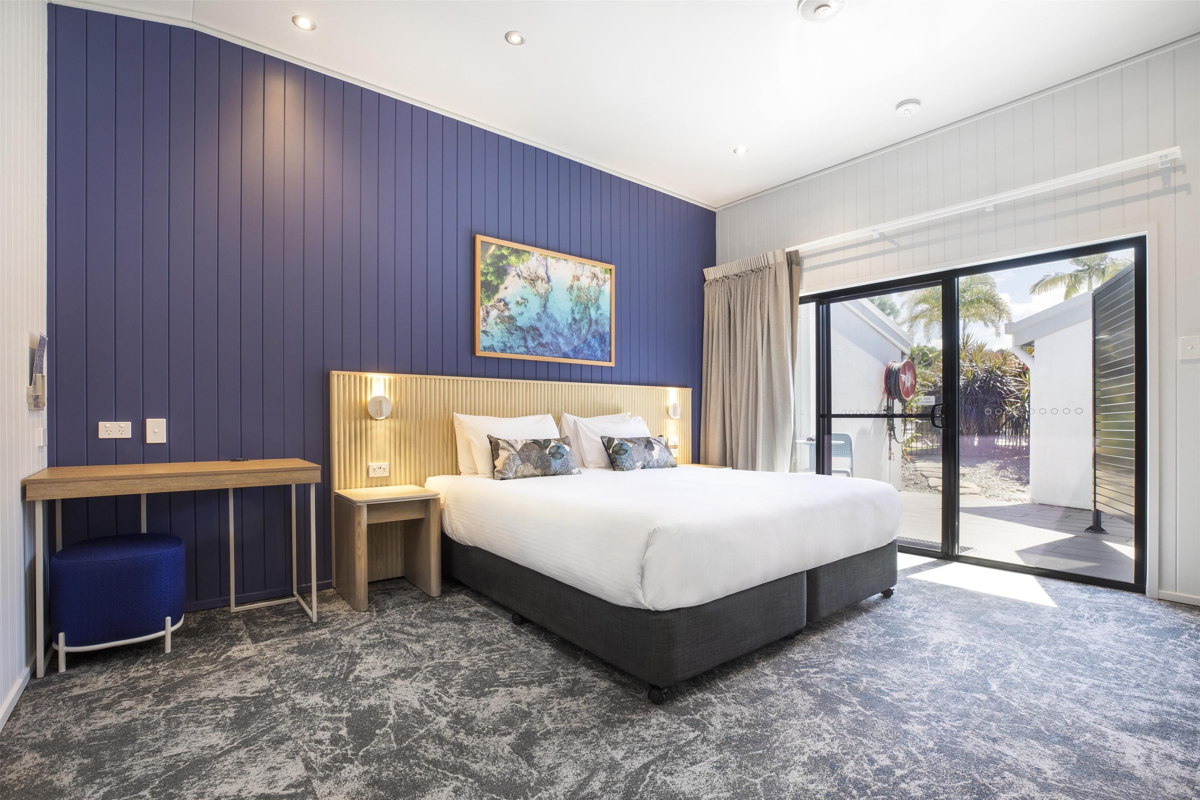 Een moderne slaapkamer met een groot bed, een bureau en uitzicht op de omgeving.
