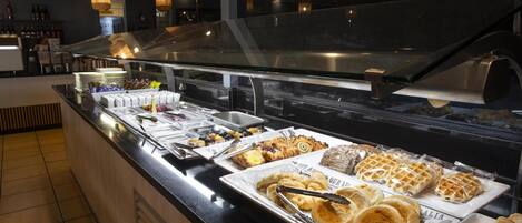 En buffet med diverse morgenmadsprodukter, herunder vafler, kager og brød.