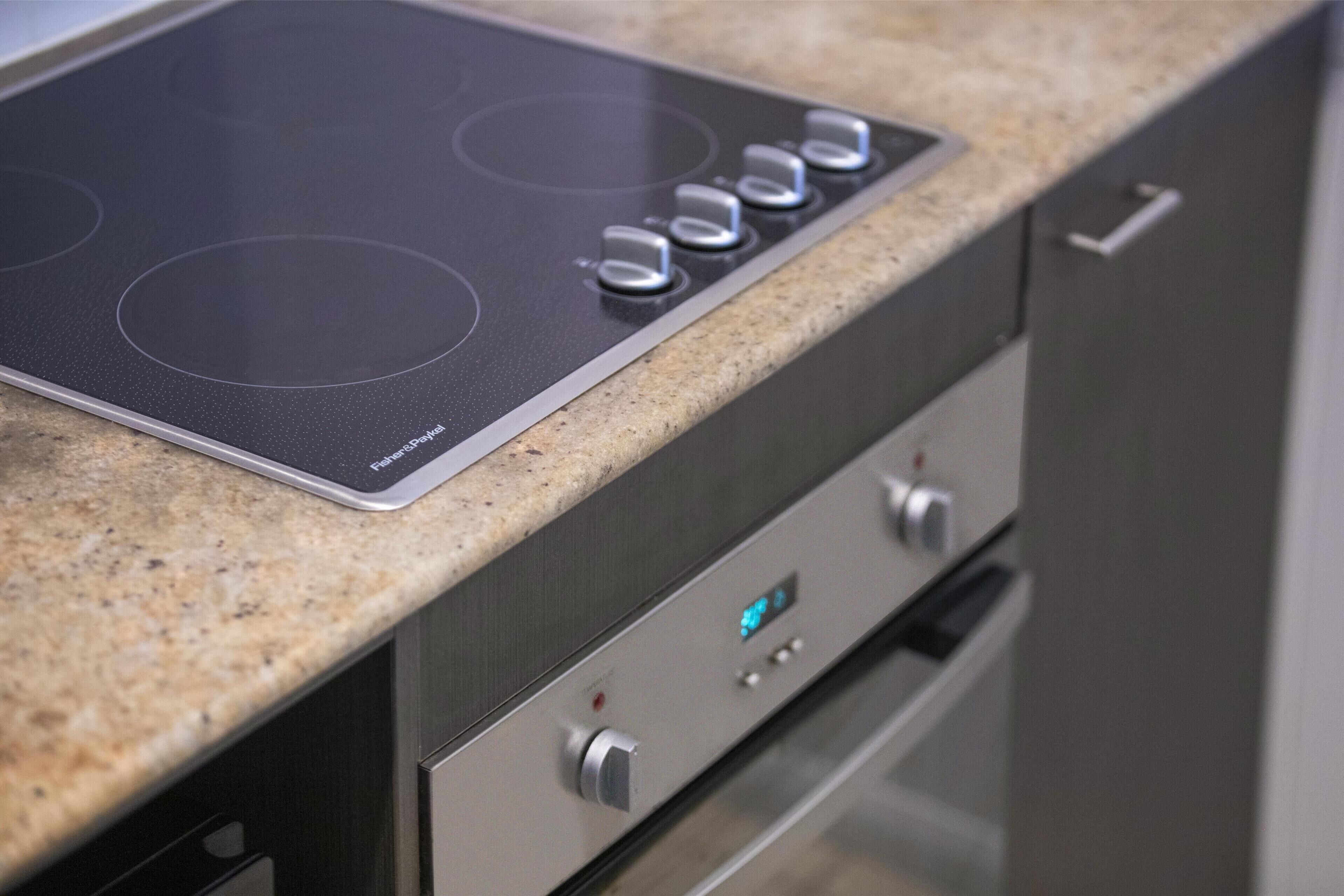 A kitchen with a built-in induction cooktop and a digital control panel.
