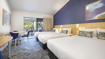 Una habitación de hotel con dos camas, un escritorio, sillas, un ventanal grande y un cuadro en la pared.