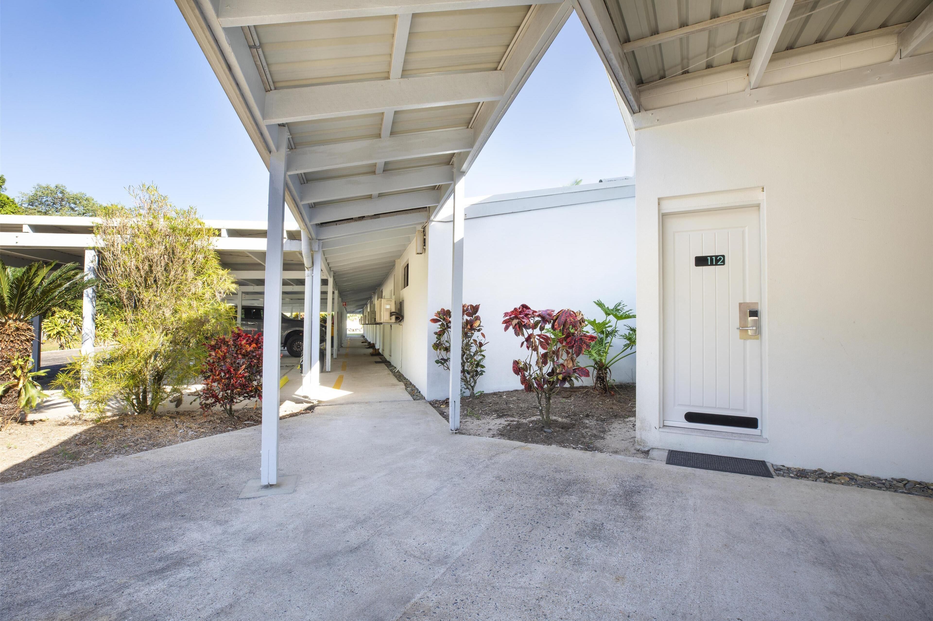 A covered walkway leading to a building with a door marked "112".