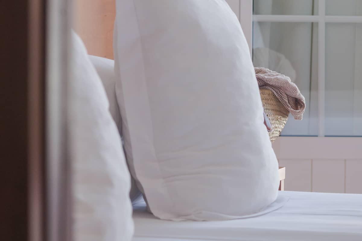A bed with white bedding and a window with a view of the outside.