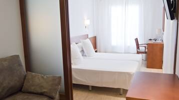 Una habitación de hotel con cama, escritorio, silla y sofá.