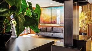 Un interior moderno con un sofá, un cuadro abstracto grande y una planta en maceta.