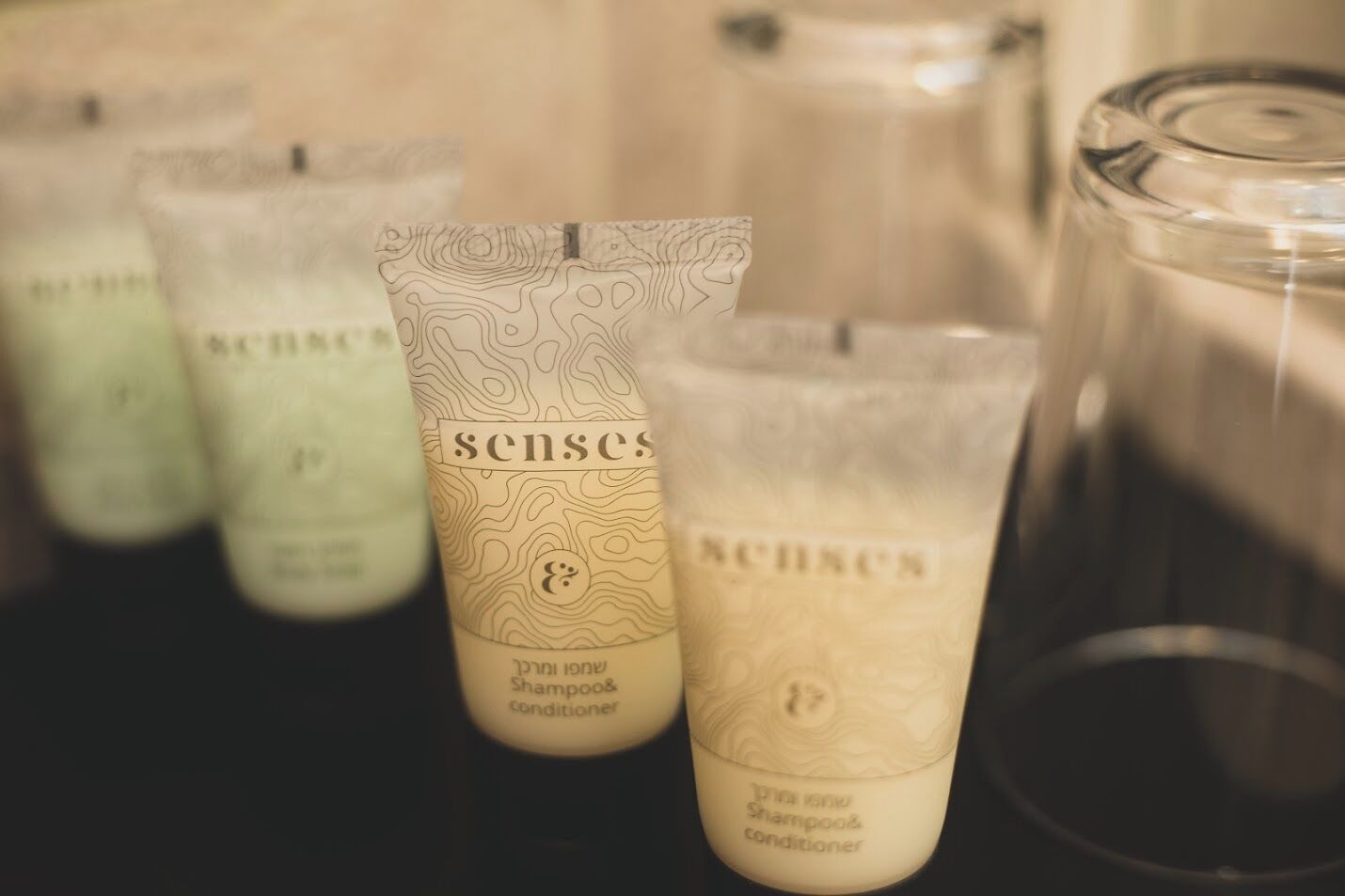 A row of bottles labeled 'Senses' with a topographic design, likely containing shampoo and conditioner.