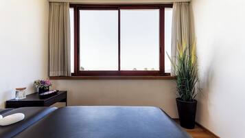 Relax in a serene space with a large bed, a window, and two potted plants.