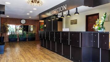 A reception area with a wooden floor, a reception desk, and a clock on the wall.