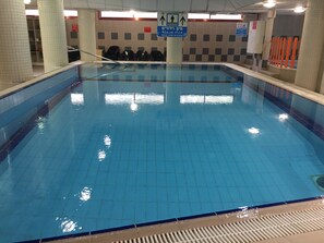 An indoor swimming pool with tiled walls and a clear water surface. - Inbar Hotel (Arad)