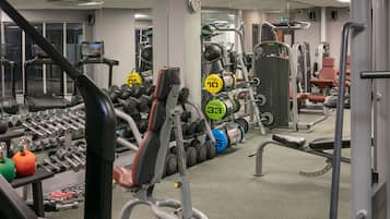 Un gimnasio con cintas de correr, mancuernas y máquinas de pesas.