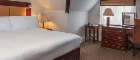 Une chambre d’hôtel avec un grand lit, un bureau avec une lampe et une commode.