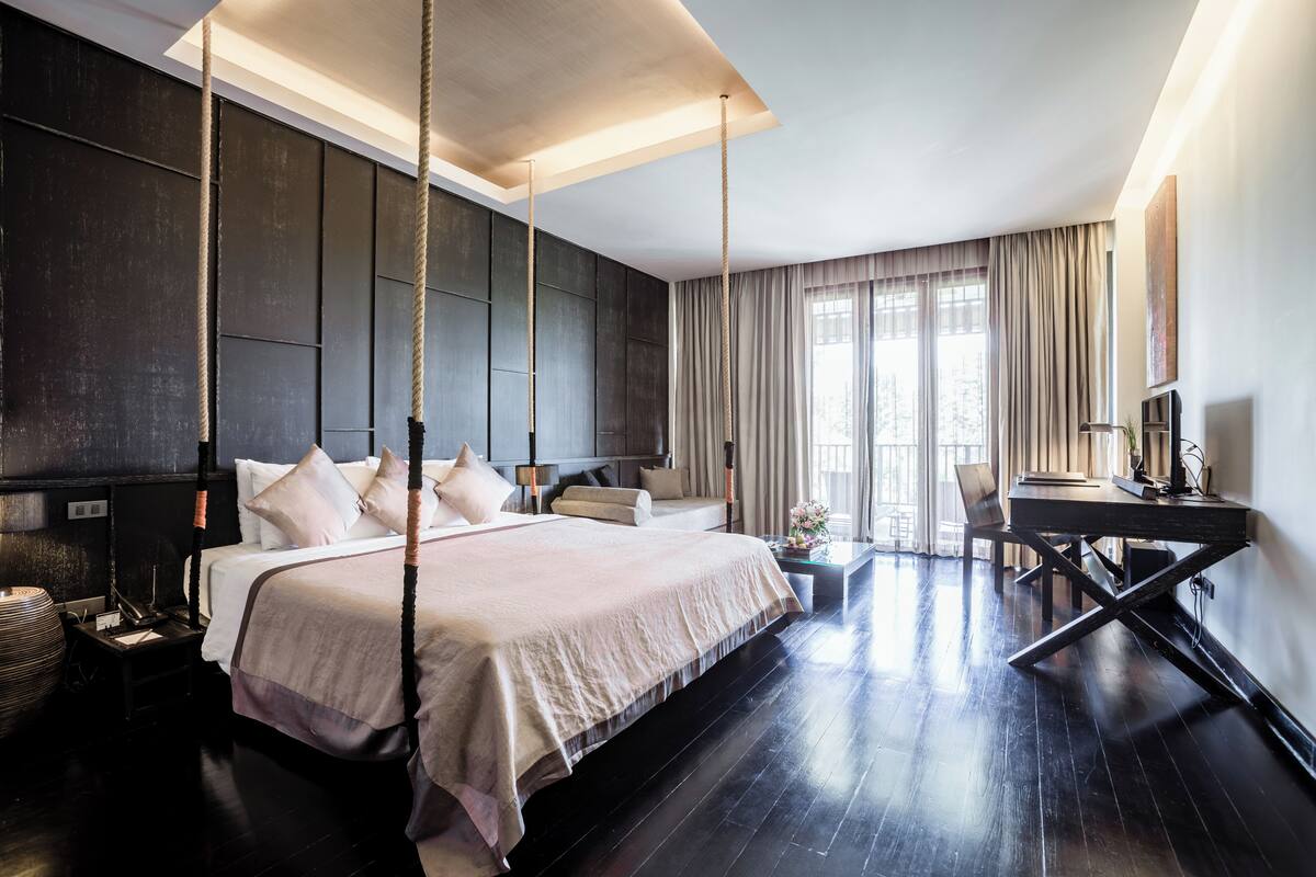 Habitación de hotel moderna con una cama grande, un escritorio y vistas al exterior.
