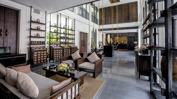 A spacious living area with a sofa, coffee table, and shelves with decorative items. - Aruntara Riverside Boutique Hotel (Chiang Mai)