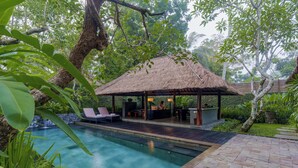 A pool area with a thatched-roof structure, lounge chairs, and a bar. - Kayumanis Ubud Private Villas & Spa (Ubud)