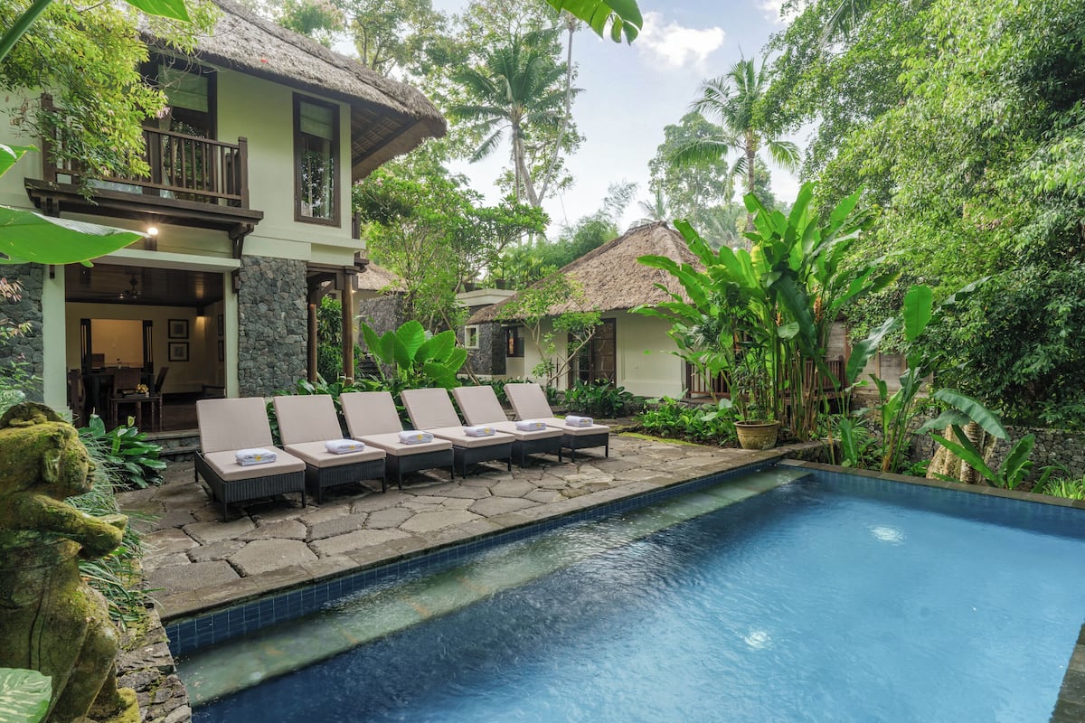 A pool area with lounge chairs and a stone pathway.