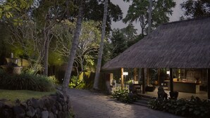 A thatched-roof building with a stone pathway leading to it, surrounded by trees and plants. - Kayumanis Ubud Private Villas & Spa (Ubud)