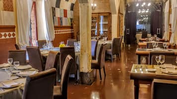 Un interior con mesas dispuestas para comer, vigas de madera y candelabros.