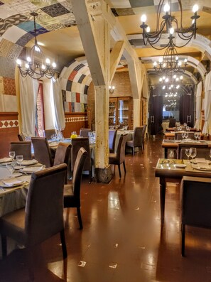 An interior with tables set for dining, wooden beams, and chandeliers. - Palacio de la Serna (Ballesteros de Calatrava)
