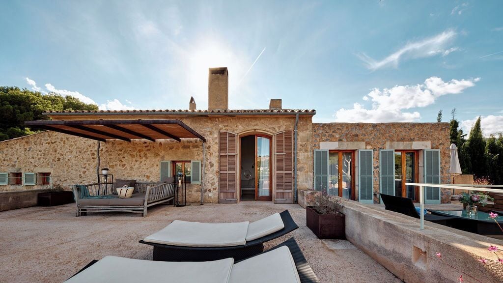 A stone building with a patio area featuring lounge chairs, a table, and a small seating area.